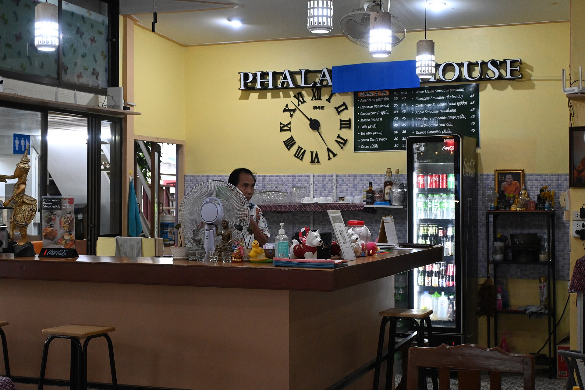 DFC 2241 Cozy corner of a small café with a counter stools a wall clock and a refrigerated display stocked with drinks