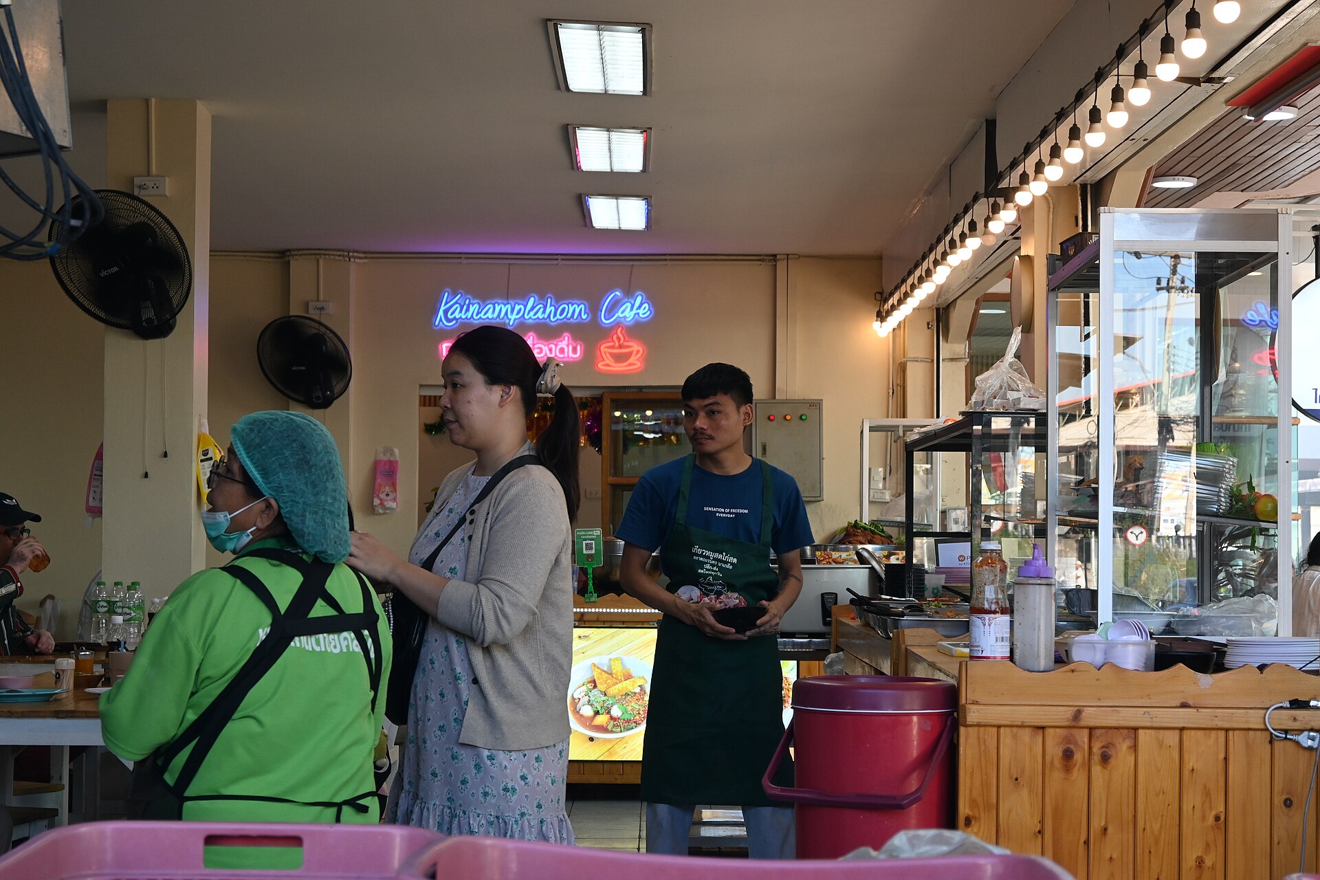DFC 3995 Busy morning at a cozy street side café   patrons chat while staff prepare fresh orders behind the counter