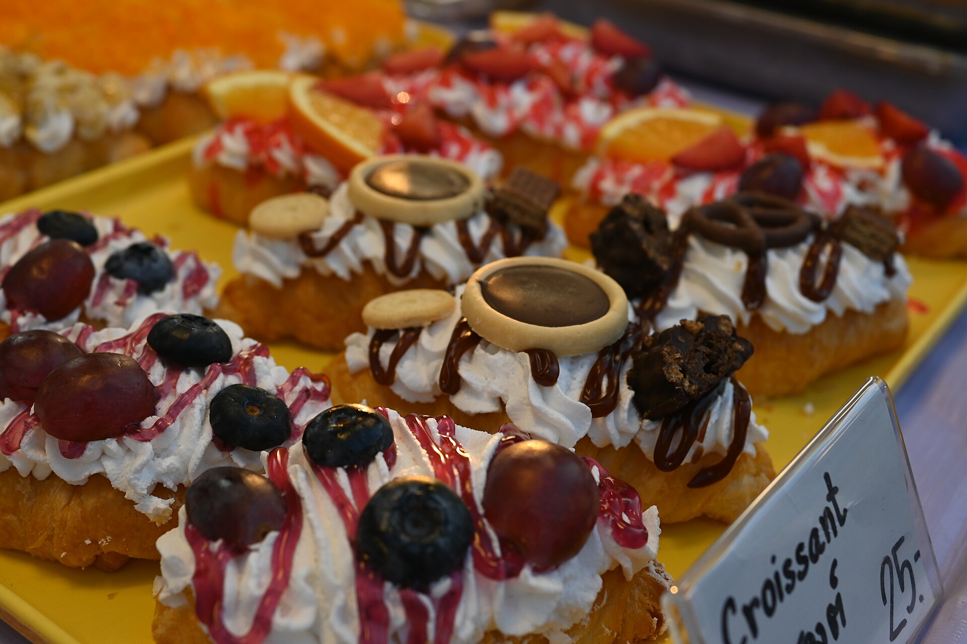 DFC 4093 Assorted mini cream topped pastries drizzled with fruit sauce and chocolate ready to tempt at the bakery counter